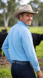 Rear three-quarter view of model wearing S.Kidman Holstein Long Sleeve Shirt in Pale Blue gingham in a rural setting.