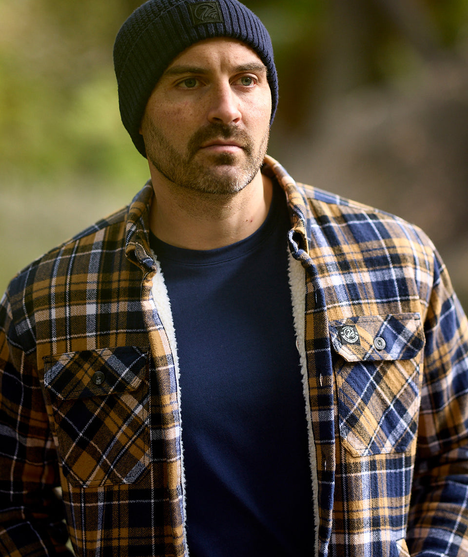 Close-up outdoor shot of Swanndri Newton Beanie blue highlighting knit texture and Swanndri logo tag.