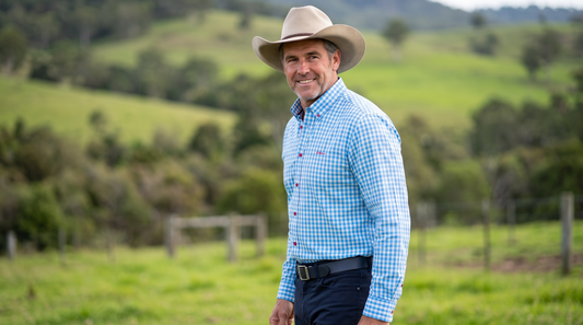 Model wearing S.Kidman Holstein Long Sleeve Shirt in Pale Blue gingham with western-style hat in a rural paddock setting.