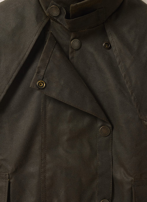 Close-up front view of Driza-Bone Kids Rider Coat showing detailed oilskin texture, storm flap, and authentic brass snap buttons.